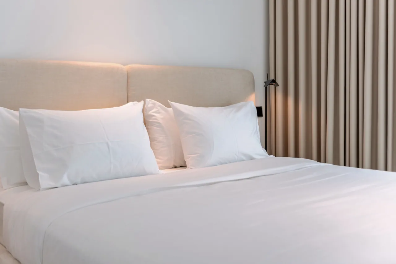 Beyaz örtülerle hazırlanmış, dört yastıklı otel yatağı